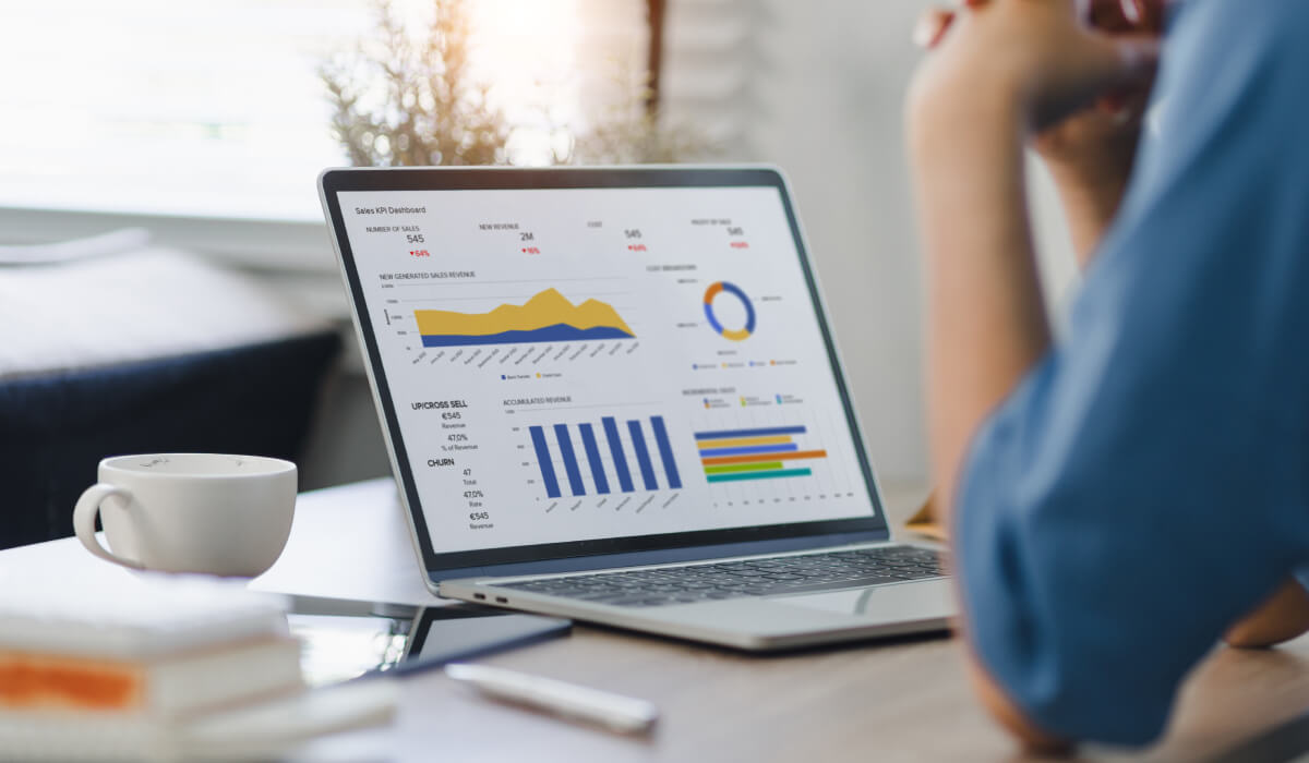 A marketing analyst reviewing detailed data charts on a laptop, showcasing the power of reporting and attribution for data-driven decision making in marketing.