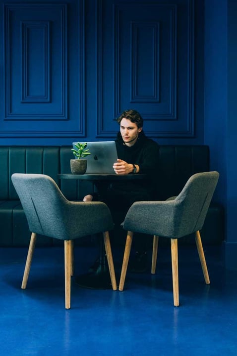 Image of an individual sitting in a blue room, focused on creating a static list in HubSpot on their laptop. The person appears engaged and concentrated, highlighting the user-friendly nature of the HubSpot interface. The blue room provides a calm and serene environment, conducive to productive work.