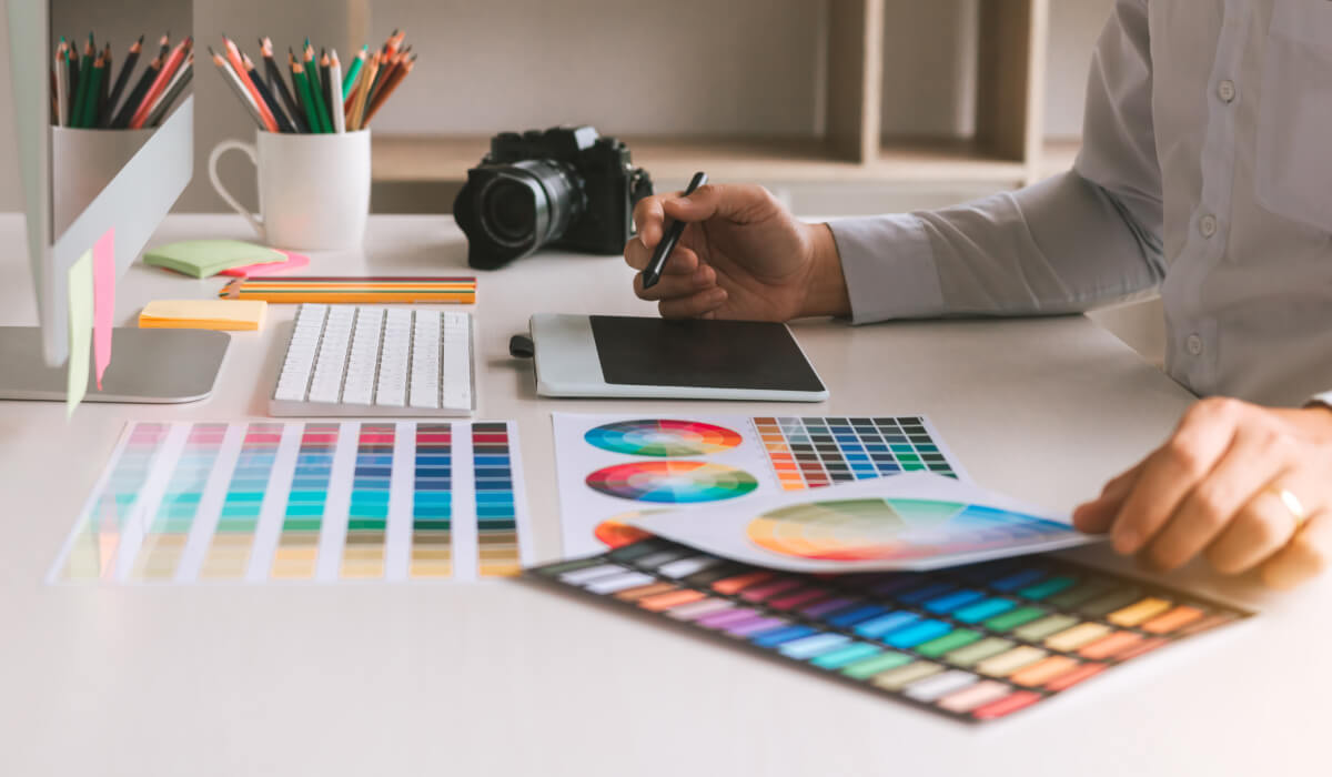 Designer working with color palettes and mood boards on a desk, showcasing the tools and techniques used in the branding process.