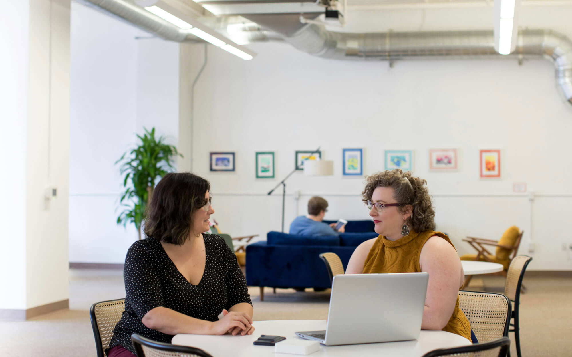 Two colleagues discussing strategy over a laptop in a coworking space