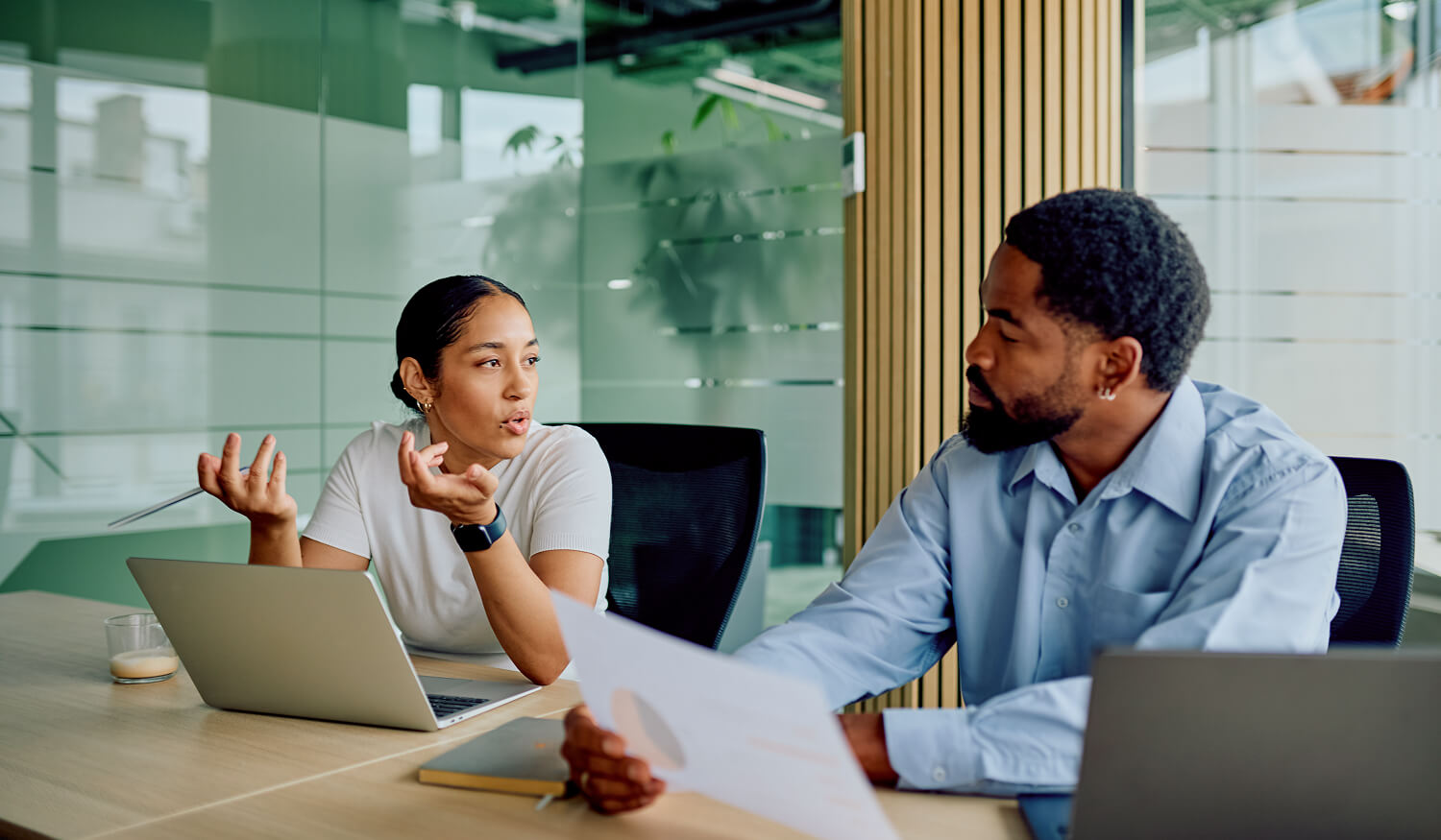 Consultant explaining campaign audit findings while a colleague reviews a printed report
