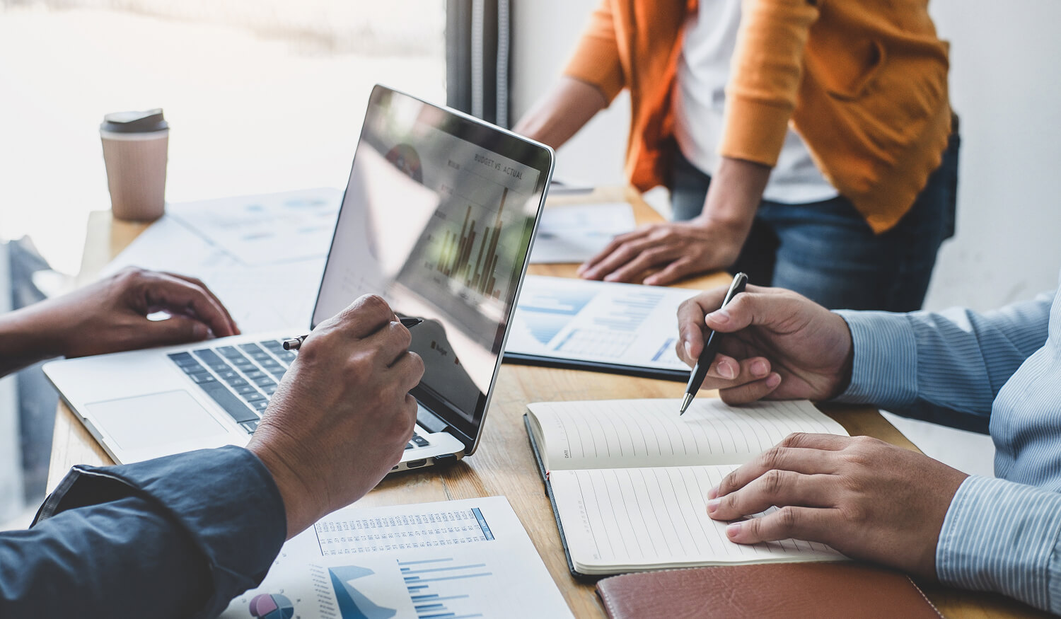 Marketing team reviewing SEO and analytics data together on a laptop and printed charts