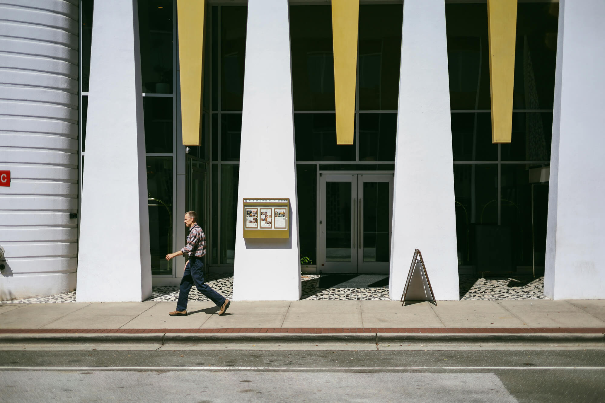 Pedestrian walking past modern white‑column façade in front of the Durham Hotel symbolizing the city’s growing international tech and business scene.
