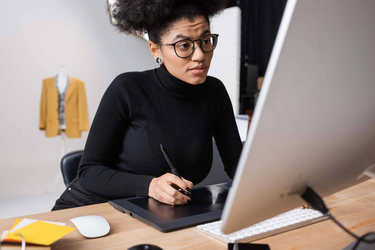 Designer using a stylus and tablet at a desktop computer, focused on uncovering the core elements of a client’s brand as part of a website project.