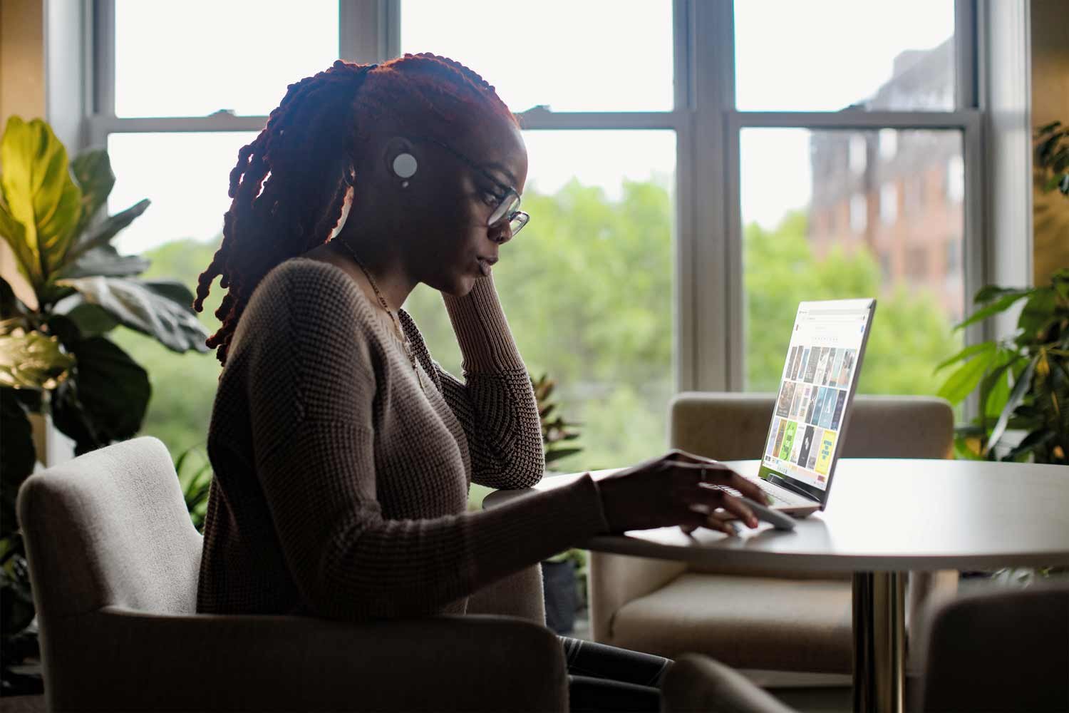 African American woman, a HubSpot expert, diligently working on her laptop. Her focus and professionalism are evident as she navigates through her tasks, fingers skillfully maneuvering on the keyboard, ready to input the next valuable piece of information.