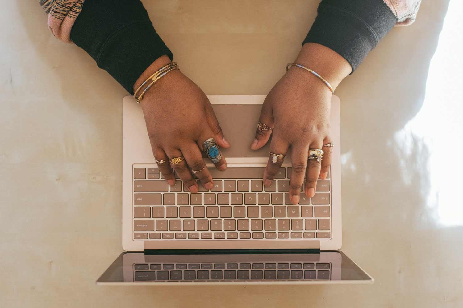 A woman is engrossed in her work, typing intently at her computer. She is diligently crafting a HubSpot workflow, her concentration and precision evident as her fingers swiftly move across the keyboard.